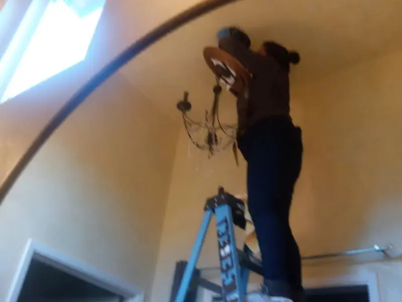 Electrician installing a chandelier in a Chandler residence